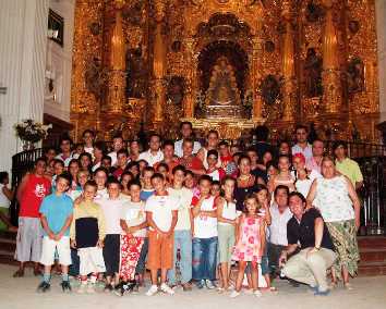 Grupo de niños, monitores y demás hermanos ante la Blanca Paloma